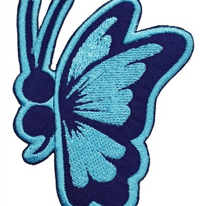 May include: Embroidered butterfly patch in shades of blue. The patch features a dark blue background with a light blue butterfly design. The butterfly has detailed wing patterns and a light blue outline.
