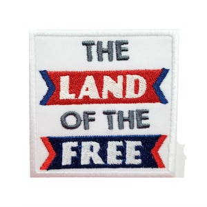 以下が含まれることがあります： 「THE LAND OF THE FREE」と赤い、白い、青い文字で刺繍された白いパッチです。