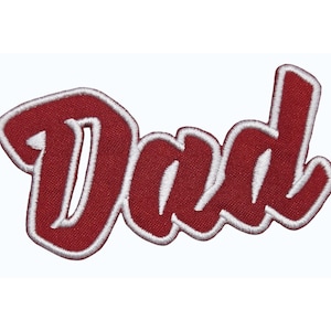 May include: A red embroidered patch with the word "Dad" in a cursive font. The letters are outlined in white, creating a contrasting effect. The patch is likely designed to be ironed or sewn onto clothing or accessories.
