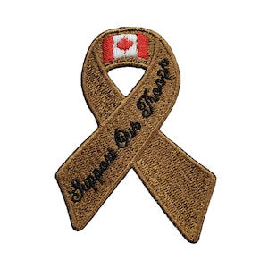 Pode incluir: Uma fita marrom com o texto "Support Our Troops" e uma bandeira canadense no centro.