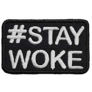 May include: Black embroidered patch with white stitching. The patch says "#STAY WOKE" in all capital letters.