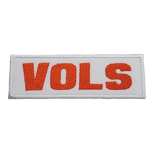 May include: White rectangular patch with the word "VOLS" in orange embroidered letters.