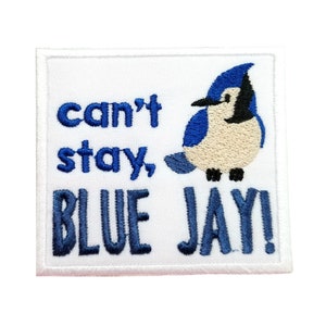 May include: Embroidered patch with the text "can't stay, BLUE JAY!" in blue lettering. A blue jay bird illustration is on the right. The patch is square with a white border and background.