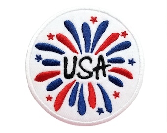 May include: A white circular patch with red and blue embroidered fireworks and the word "USA" in black lettering.