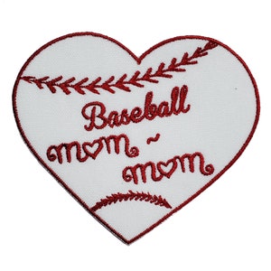 Pode incluir: Etiqueta branca em forma de coração com costuras bordadas vermelhas. A etiqueta apresenta um gráfico de beisebol e o texto "Baseball mom - mom".
