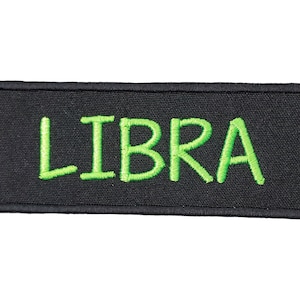 May include: Black fabric patch with green embroidered text that reads "LIBRA".