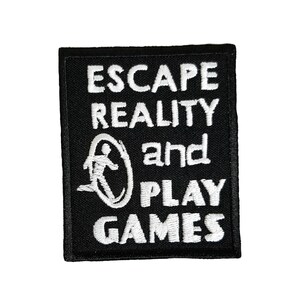 Könnte beinhalten: Schwarzer gestickter Aufnäher mit weißem Text, der "Escape Reality and Play Games" lautet. Eine weiße Silhouette einer laufenden Person in einem Kreis befindet sich zwischen den Wörtern "Reality" und "and".