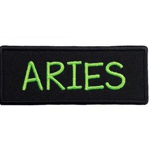 May include: Black fabric patch with green embroidered text that reads "ARIES".