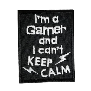 Könnte beinhalten: Schwarzer gestickter Aufnäher mit weißem Text, der "Ich bin ein Gamer und ich kann nicht ruhig bleiben" lautet, mit Blitzsymbolen.