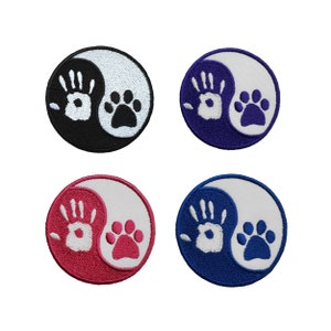 Peut inclure: Quatre patchs brodés en forme de symbole yin yang. Les patchs sont noir et blanc, bleu et blanc, rouge et blanc et violet et blanc. Chaque patch présente une empreinte de main blanche d'un côté et une empreinte de patte blanche de l'autre.