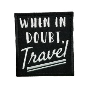 May include: Black embroidered patch with white text that reads "When in doubt, Travel!"