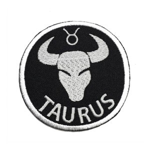 May include: A black and white embroidered patch with a bull's head and the word "TAURUS" in a circle.