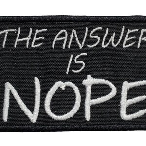 May include: Black embroidered patch with white text that reads "The answer is nope."