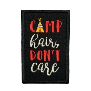 May include: Black embroidered patch with the text "Camp hair don't care" in white and red lettering. A small yellow and red tent graphic is above the word "Camp".