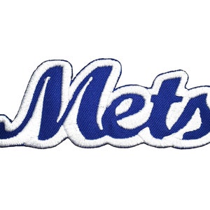 Może przedstawiać: Naszywka haftowana w kolorze niebieskim i białym z napisem "Mets" w stylizowanym kroju pisma.