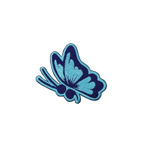 May include: Embroidered butterfly patch in shades of blue. The butterfly has a dark blue outline and a light blue interior with detailed wing patterns. The patch is designed for application on clothing or accessories.