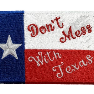 Puede incluir: Parche bordado con el diseño de la bandera de Texas. El parche es rectangular y presenta una franja vertical azul, una franja horizontal blanca y una franja horizontal roja. El texto "Don't Mess With Texas" está bordado.