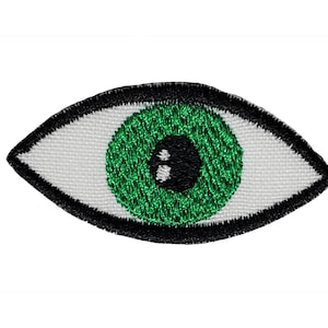 May include: Green eye embroidered patch with a black outline. The eye is on a white fabric background.