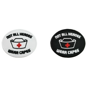 Könnte beinhalten: Zwei gestickte Bügelbilder, eines weiß und eines schwarz, mit dem Text "Not all heroes wear capes" und einem stilisierten Bild einer Krankenschwestermütze mit einem roten Kreuz.