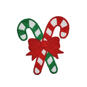 May include: Two red and green candy canes with white stripes are tied together with a red bow. The candy canes are crossed over each other.