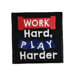 May include: A black embroidered patch with the words "WORK Hard, PLAY Harder" in white lettering. The word "WORK" is on a red banner, and "PLAY" is on blue tiles.