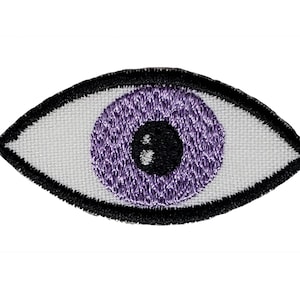 May include: Purple embroidered eye patch with a black outline. The eye patch is made of white fabric.