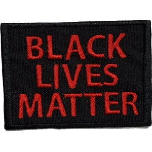 May include: Black Lives Matter patch with red embroidered text on a black fabric background.