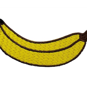 May include: A yellow felt banana with a brown outline. The banana is curved and has a brown stem.