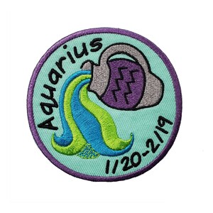 May include: A round, teal blue embroidered patch with a purple and gray water pitcher pouring water. The water is blue and green. The text "Aquarius 1/20-2/19" is embroidered around the edge of the patch.
