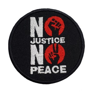 May include: Black embroidered patch with white text that reads "No Justice No Peace" and two red fists, one raised and one with two fingers extended.