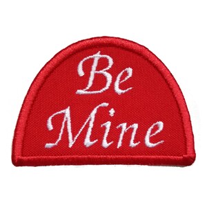 May include: Red fabric patch with white embroidered text that reads "Be Mine".