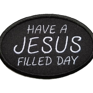 May include: Black oval patch with white embroidered text that reads "Have a Jesus Filled Day."