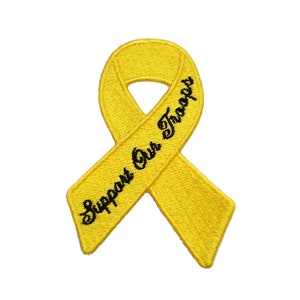 Pode incluir: Etiqueta bordada de fita amarela com o texto "Support Our Troops" em preto.