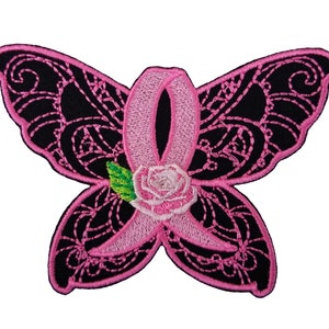 May include: Pink embroidered butterfly with a pink ribbon and a white rose in the center. The butterfly has black wings with intricate designs.