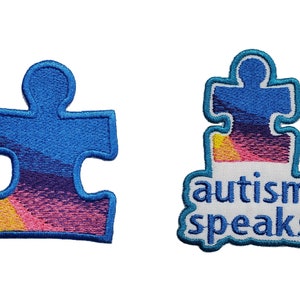 May include: Two blue and white embroidered patches featuring a puzzle piece design. The larger patch reads "autism speaks" in blue lettering.
