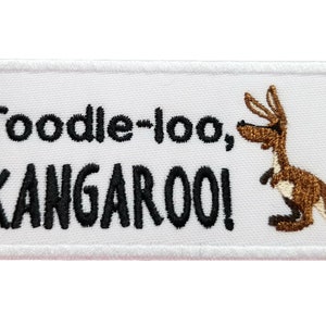 Può includere: Toppa ricamata bianca con testo nero che recita "Toodle-loo, KANGAROO!" e un canguro di cartone marrone con un occhio nero.
