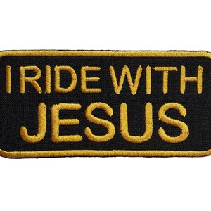 May include: Black rectangular patch with the embroidered text "I RIDE WITH JESUS" in gold. The patch has a gold border and is likely designed to be sewn onto clothing or accessories.