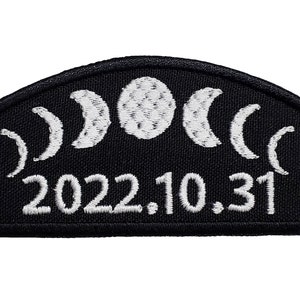 Puede incluir: Parche bordado negro con lunas crecientes blancas y la fecha 2022.10.31.