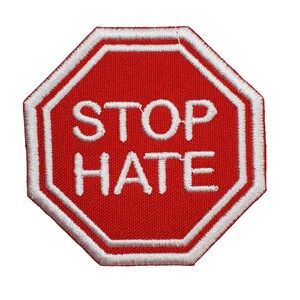 May include: Red octagonal stop sign with white border and white text that reads "STOP HATE".