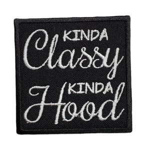 May include: Black square patch with white embroidered text that reads "KINDA Classy KINDA Hood". The patch has a black border and is likely designed to be sewn or ironed onto clothing or accessories.