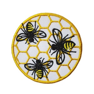 May include: A round embroidered patch with three black and yellow bees on a white background. The bees are surrounded by a yellow honeycomb pattern.