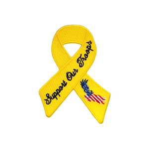Pode incluir: Fita amarela com as palavras "Support Our Troops" bordadas. Uma bandeira americana com uma águia é bordada na fita.