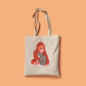 May include: A cream-coloured tote bag with a watercolour illustration of two orangutans. The larger orangutan is reddish-orange, embracing a smaller grey orangutan. The bag has long handles, ideal for carrying items.