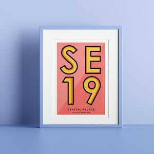 May include: A framed print with a pink background and yellow text that reads "SE19" and "CRYSTAL PALACE SOUTH LONDON".