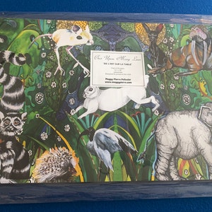 May include: A colorful illustration of various animals in a jungle setting. The animals include a lemur, a rabbit, a bird, a hedgehog, an elephant, a mouse, and a walrus. The illustration is on a green background with a white text box that says "One Upon a Many Lives We Just Sit Sur La Table".