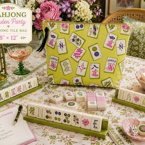 May include: A lime green zippered pouch featuring a repeating pattern of colourful mahjong tiles. The bag measures 20.32 cm by 30.48 cm and is displayed alongside mahjong tiles on green racks, a notepad, and a glass of pink liquid on a floral tablecloth.