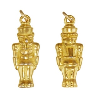 May include: A pair of gold-tone nutcracker charms. Each charm features a detailed design of a nutcracker with a hat, beard, and a sword.