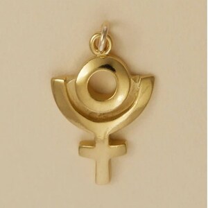 May include: A gold pendant charm in the shape of the symbol for Venus, a circle with a cross underneath, with a ring around the circle.