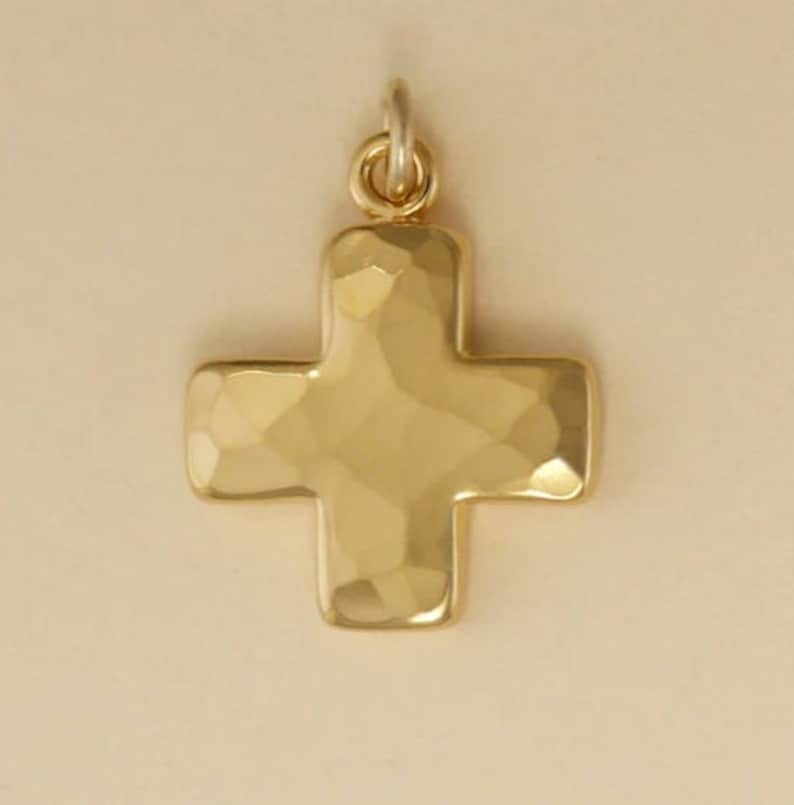 Pu&ograve; includere: Un ciondolo a forma di croce martellata in oro. La croce &egrave; un design semplice con una superficie testurizzata.