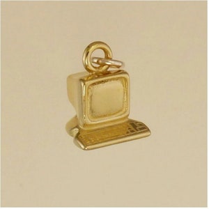 May include: A gold-colored computer charm with a monitor and keyboard. The charm has a loop at the top for attaching to a necklace or bracelet. The computer charm is a miniature replica of a classic desktop computer.